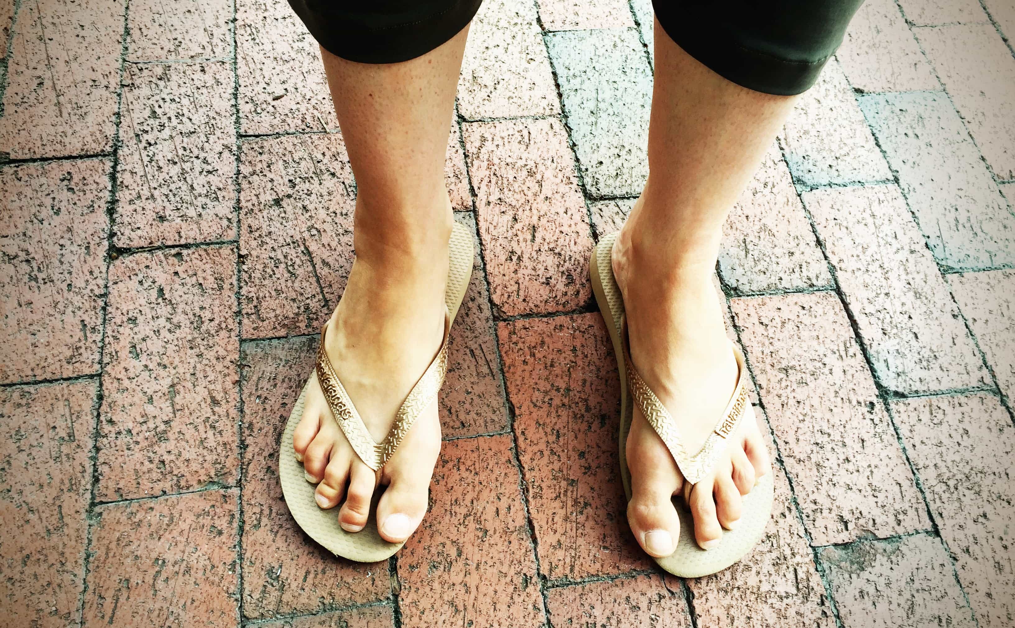 A photograph of the author's feet in gold flip-flops.