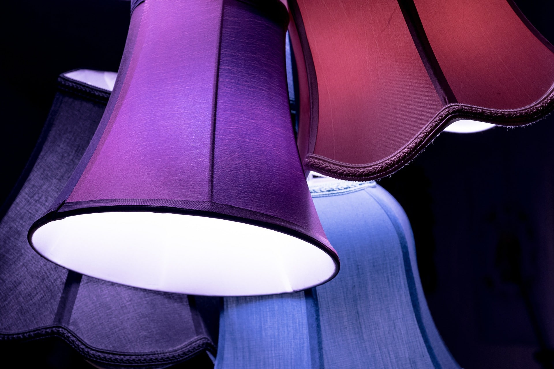 Alt Text: Photograph of four colorful lampshades on a black background, all askew.