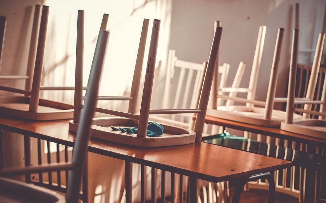 Alt Text: A Photograph of an empty classroom with chairs stacked on the desks